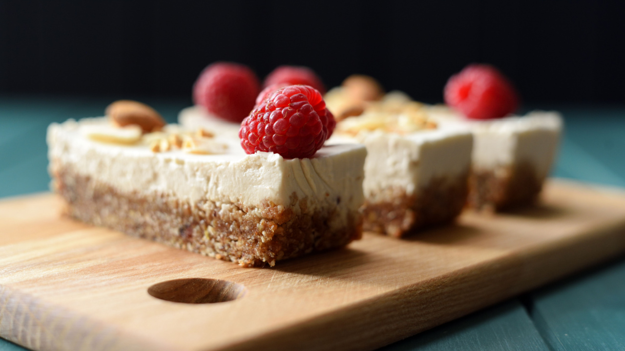 Vegan sugar free dessert. Coconut milk cheesecake bars decorated with raspberries, almonds and coconut flakes