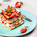 Summer dessert, classic tiramisu with strawberries decorated with mint leaves.