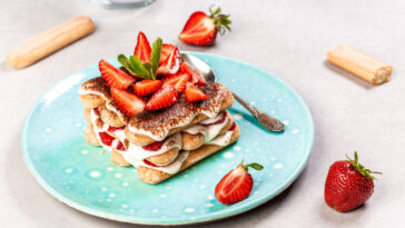 Summer dessert, classic tiramisu with strawberries decorated with mint leaves.