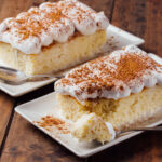 Two pieces of a delicious three milk cake dessert on a wooden background