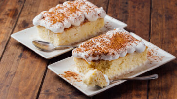 Two pieces of a delicious three milk cake dessert on a wooden background
