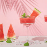 watermelon cocktail glasses and watermelon slices with pink palm leaf.