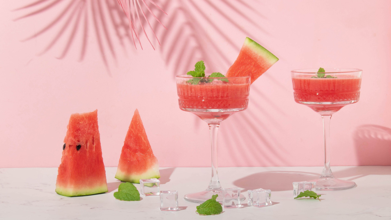 watermelon cocktail glasses and watermelon slices with pink palm leaf.