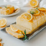 Lemon pound cake topped with icing sugar glaze, lemon slices and rosemary.