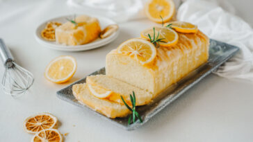 Lemon pound cake topped with icing sugar glaze, lemon slices and rosemary.