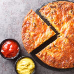 Homemade crispy cheeseburger pie served with sauces close-up on a slate board on the table.