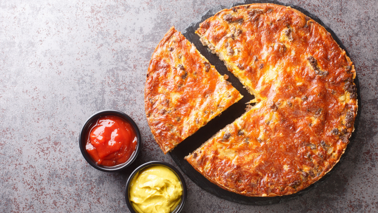 Homemade crispy cheeseburger pie served with sauces close-up on a slate board on the table.