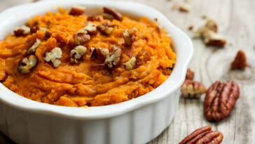 Mashed Sweet Potatoes with Pecans on wooden table.