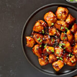 Teriyaki chicken on plate over black stone background with free text space.