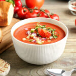 Bowl with tasty gazpacho on wooden background