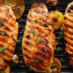 Grilled chicken breasts with thyme, garlic and lemon slices on a grill pan