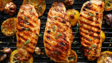 Grilled chicken breasts with thyme, garlic and lemon slices on a grill pan