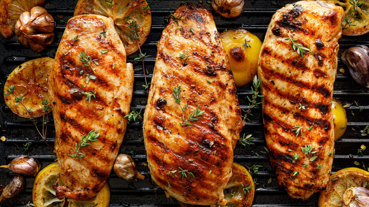 Grilled chicken breasts with thyme, garlic and lemon slices on a grill pan