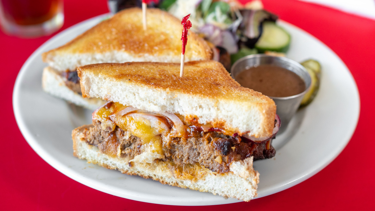 Meatloaf sandwich with melted cheddar cheese and a side salad.