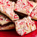 Festive red holiday plate filled with chocolate peppermint bark candy pieces