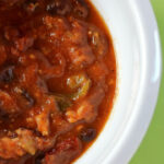 tasty turkey pumpkin chili in white bowl with green background