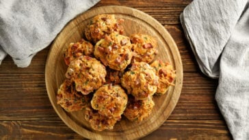 Wooden board with tasty sausage balls on table