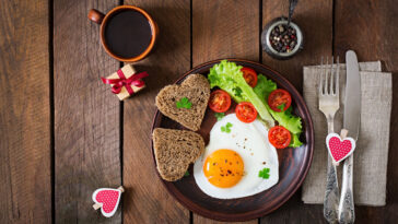 Breakfast on Valentine's Day - fried eggs and bread in the shape of a heart and fresh vegetables.