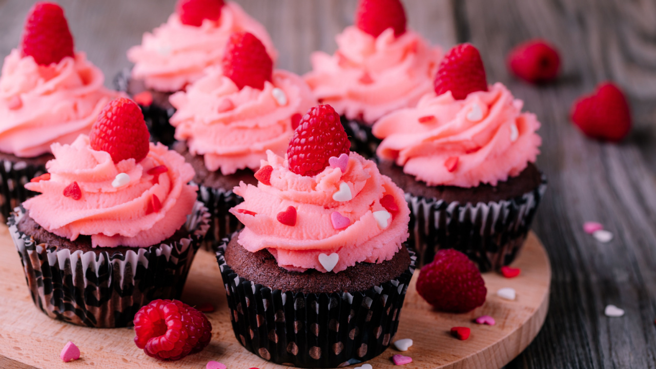 Chocolate cupcakes with pink cream, sugar hearts and fresh raspberries for St. Valentine's Day.